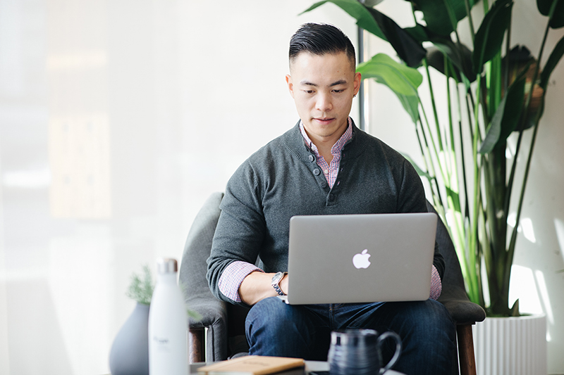 Nelson Soh working on his laptop while sitting in an armchair inside an office