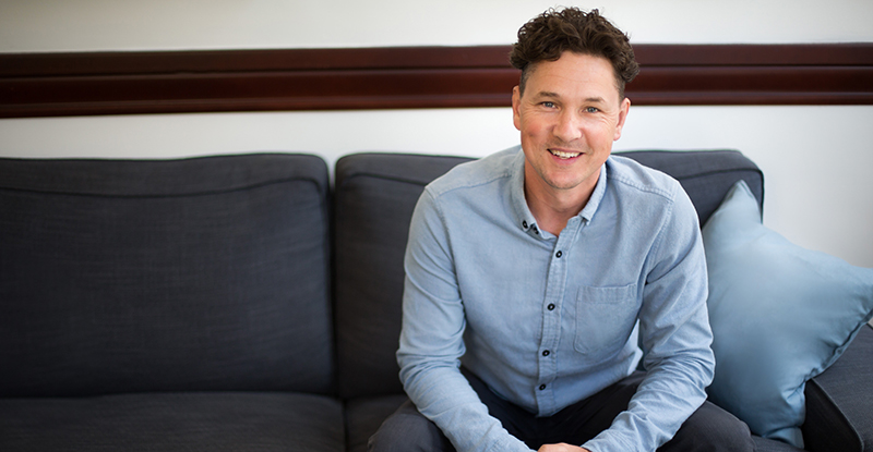 Julien Francois sitting on a couch and smiling