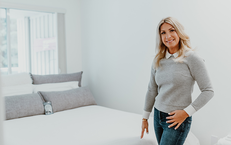 Jane stands proudly in front of a nicely organized bedroom