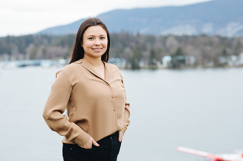 Kamani Bikadi standing in front of the ocean with Stanley Park and mountains in the distance