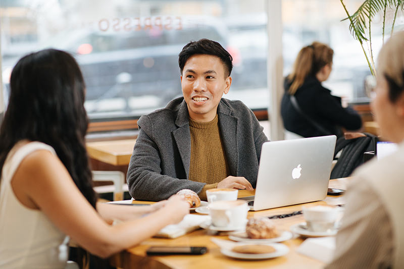 Karina Pangilinan, Tony Huynh, and Frederick Wong having coffee and working on a laptop in a cafe