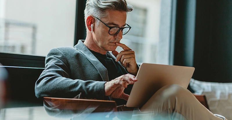 Man sitting in an easy chair listening to something on his laptop