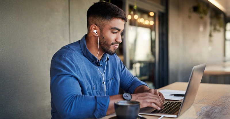 Man, earphones or laptop typing in cafe or restaurant for university, college or school studying with learning podcast app.