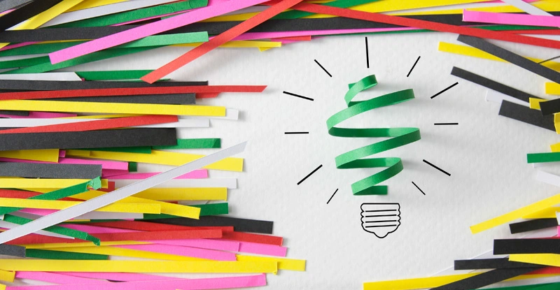 Idea symbolized by a curly strip of green paper over a drawn lightbulb base