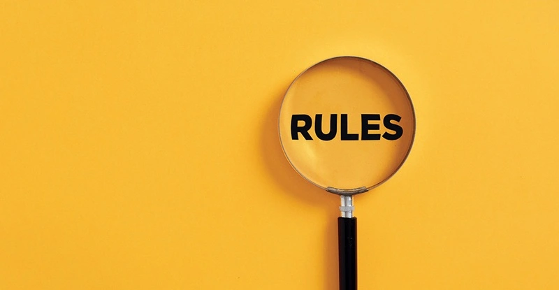Magnifying glass looking at the word "RULES" on a yellow background
