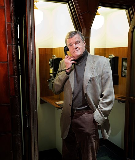 David Bowra, F C P A, F C A, author of Banking on Murder, poses in front of an old telephone booth